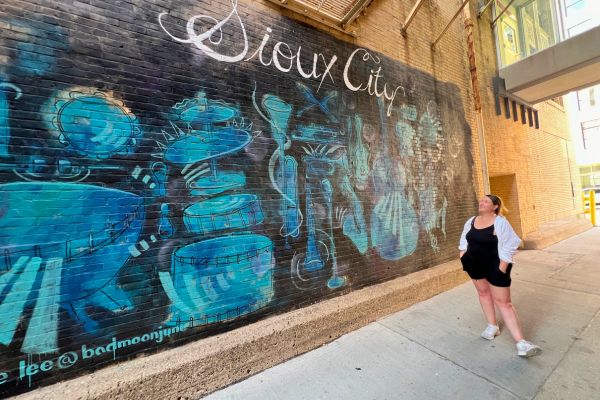 Kim standing near a Sioux City mural in downtown Sioux City